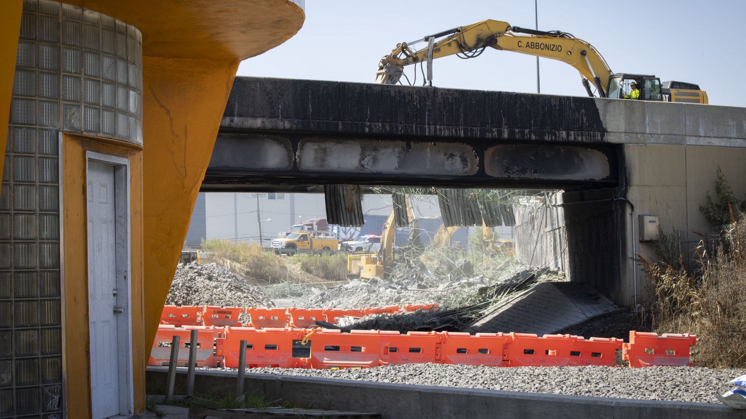 A yellow piece of construction equipment sits atop I-95 working to clear debris from the site of the bridge collapse